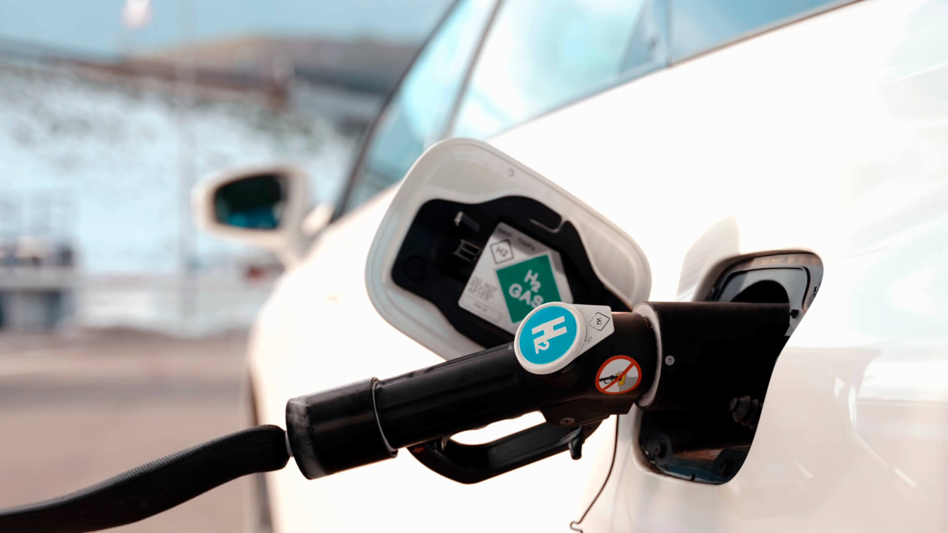 close-up of a hydrogen dispenser, refueling a white hydrogen fuel cell car parked at a hydrogen refueling station located in nature